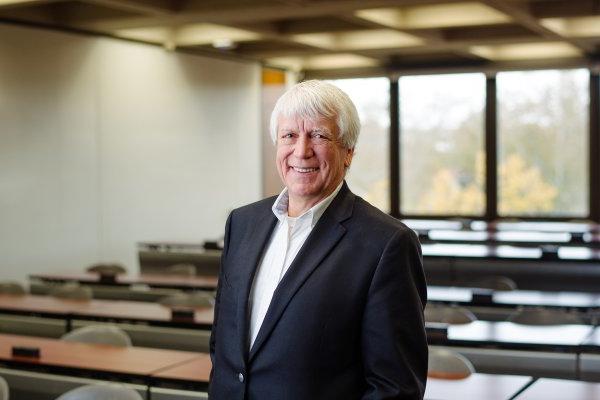 David Young Miller, Class of 1969, stands in a classroom smiling.